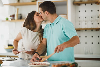 Happy couple kissing while cooking breakfast in modern kitchen