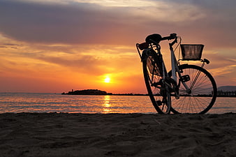 Silhouette of bicycle on beach at sunset