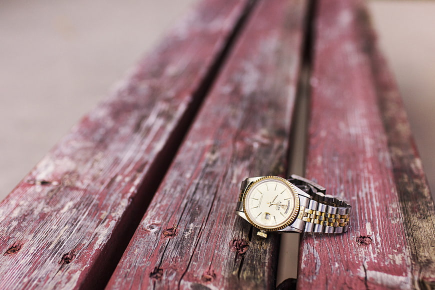 Vintage two-tone watch on weathered red wooden bench
