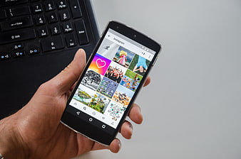 Hand holding smartphone with Instagram app on screen