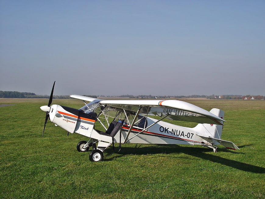 White ultralight aircraft parked on grassy airfield