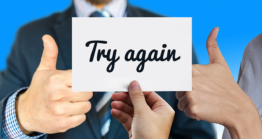 Businessmen holding sign saying try again with thumbs up