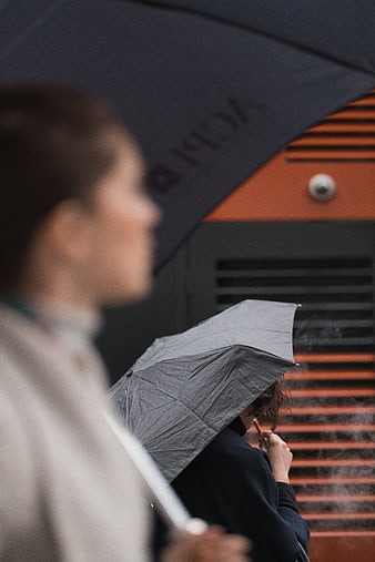 Woman smoking under umbrella in rainy city street