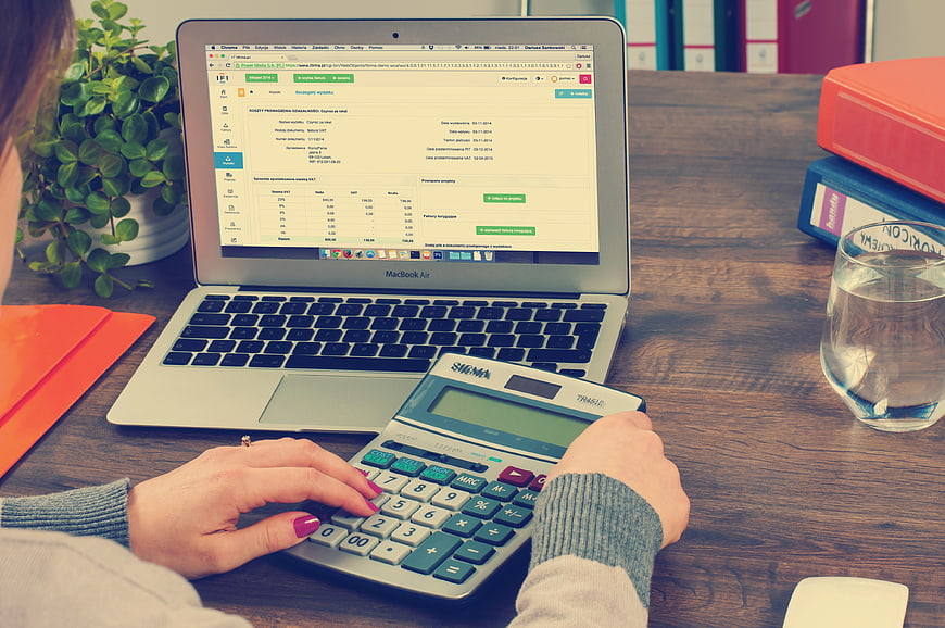 Woman using calculator and laptop for accounting work