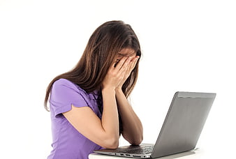 Stressed woman covering face with hands at laptop