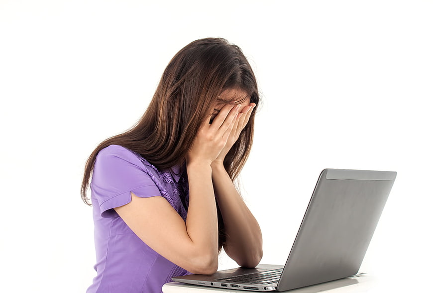 Stressed woman covering face with hands at laptop