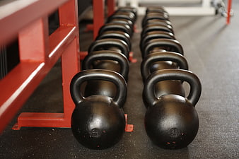 Rows of black kettlebells on gym floor