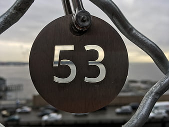 Close-up of metal number 53 sign on railing