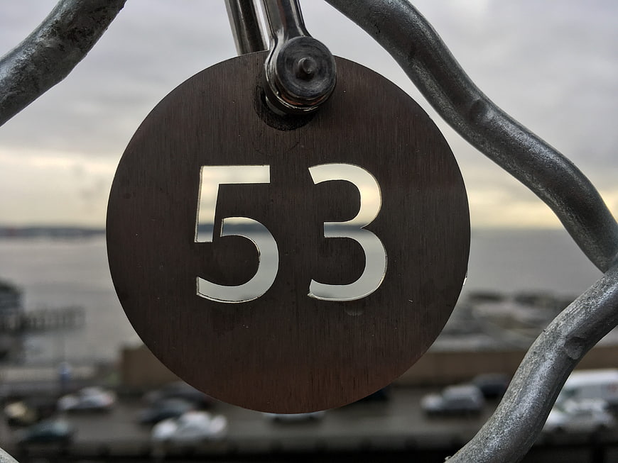 Close-up of metal number 53 sign on railing