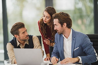 Business team collaborating around laptop in modern office