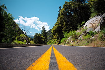 Winding Mountain Road with Yellow Lines and Blue Sky