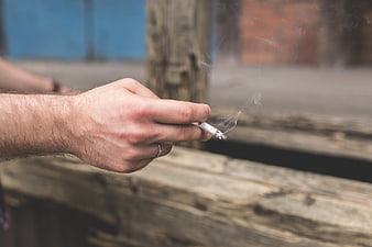 Close-up of hand holding smoking cigarette with smoke