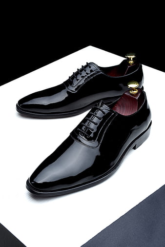 Black Patent Leather Oxford Shoes With Shoe Trees On White Surface