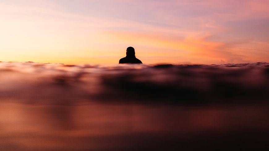 Silhouette of person swimming in ocean at sunset