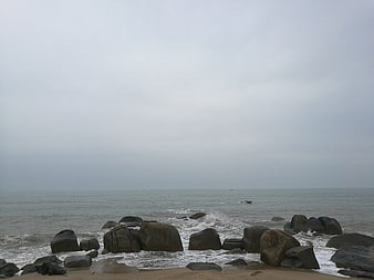 Overcast rocky beach with gray sea and distant boat