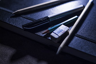Dark moody stationery on black notebook with blue lighting