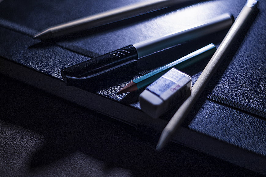 Dark moody stationery on black notebook with blue lighting