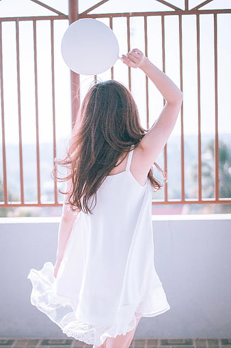 Woman in White Dress Holding White Balloon on Balcony