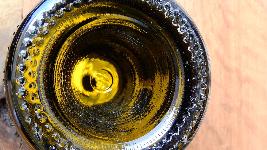 Top-down view of green wine bottle opening on wood