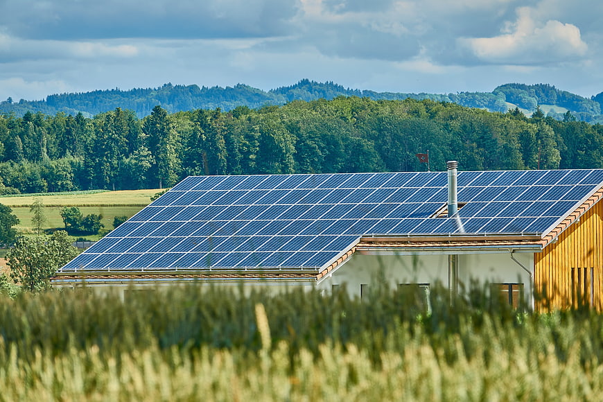 Solar Panels on Rural House Roof with Green Hills