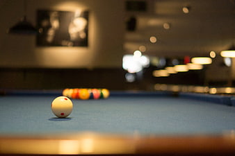 Close-up of cue ball on blue pool table with blurred background