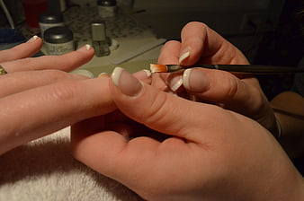 Close-up of hands applying French manicure nail design with brush