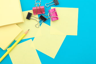 Yellow sticky notes and binder clips on blue background