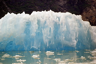 Massive Blue Glacier Face with Floating Ice Chunks in Water
