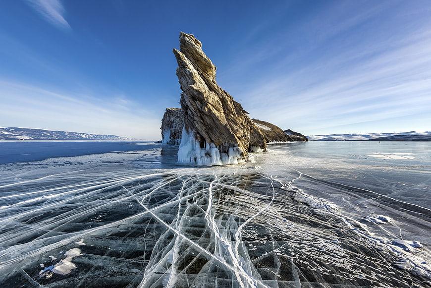 Frozen Lake Landscape with Jagged Rock Formation and Ice Cracks