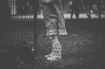 Child in Rain Boots Standing by Rabbit Cage