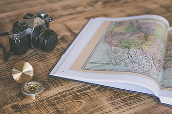 Vintage camera, compass, and open map on rustic wooden table