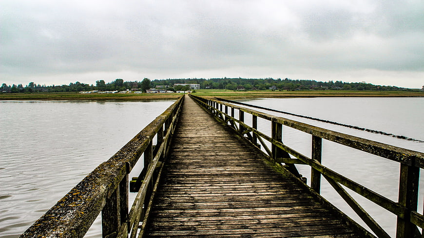 Wooden pier extending over calm water on an overcast day