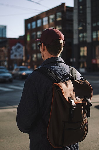 Man with Backpack and Cap Walking in City