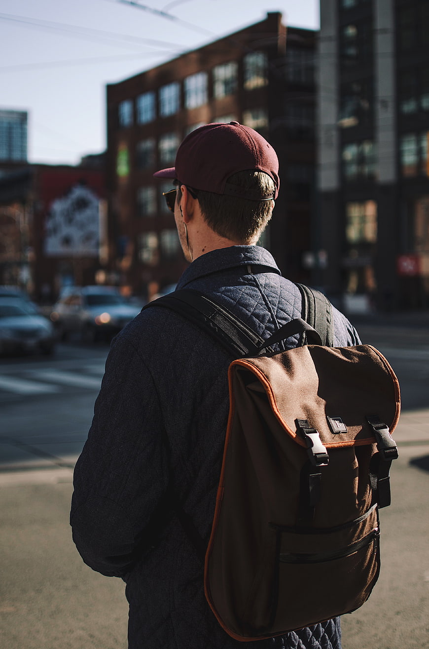 Man with Backpack and Cap Walking in City