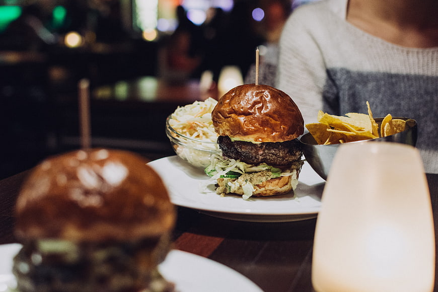 Juicy beef burger with coleslaw and chips in a restaurant