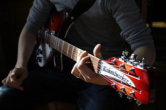 Close-up of hands playing red Rickenbacker electric guitar