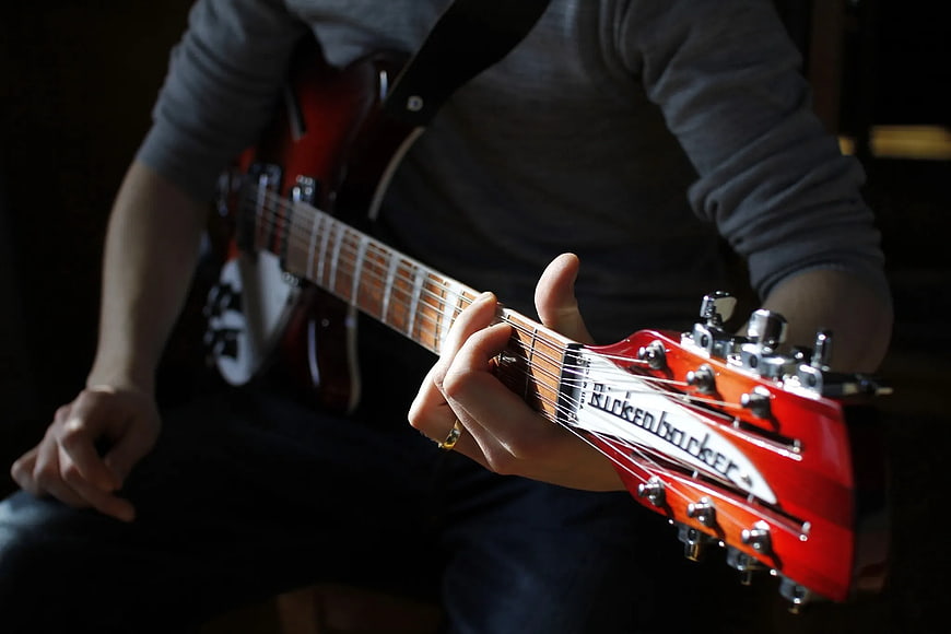 Close-up of hands playing red Rickenbacker electric guitar