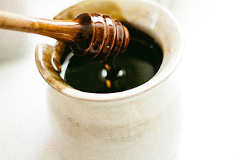Close-up of wooden honey dipper in ceramic jar