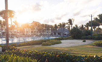 Luxury tropical resort pool at sunset with palm trees