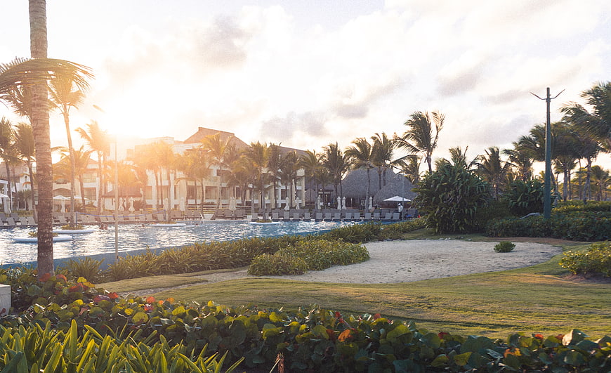 Luxury tropical resort pool at sunset with palm trees