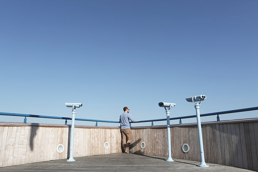 Man looking out from observation deck with binoculars