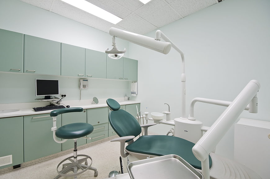 Modern dental office interior with green chair and equipment