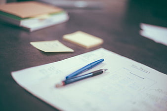 Blue pens on desk with papers and sticky notes