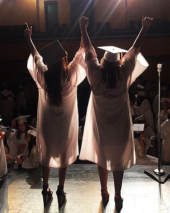Two Graduates Celebrating on Stage with Raised Arms