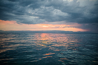 Dramatic Sunset Over Ocean with Stormy Clouds and Golden Reflections