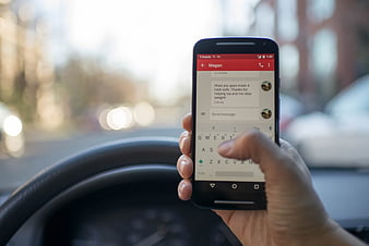 Hand texting on smartphone while driving car