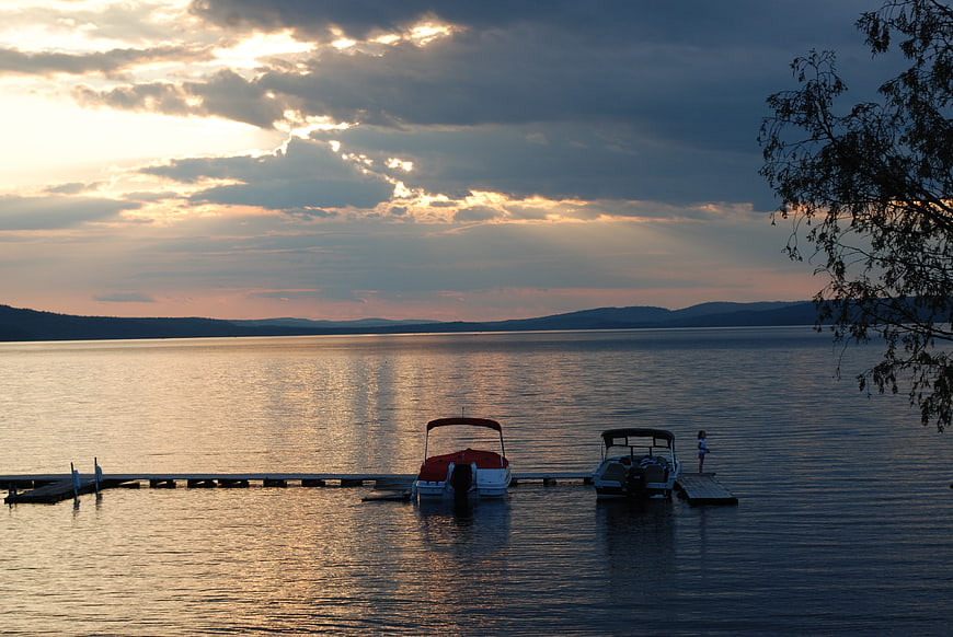 Serene Lake Sunset with Docked Boats and Distant Hills