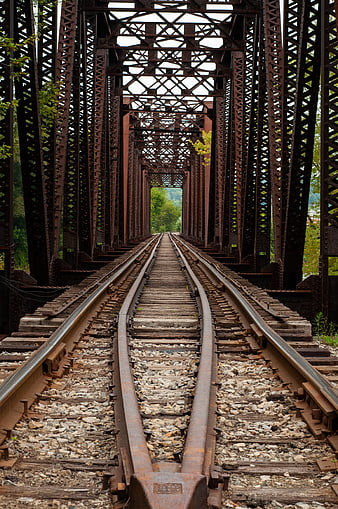 Rusty railroad tracks on an old iron truss bridge