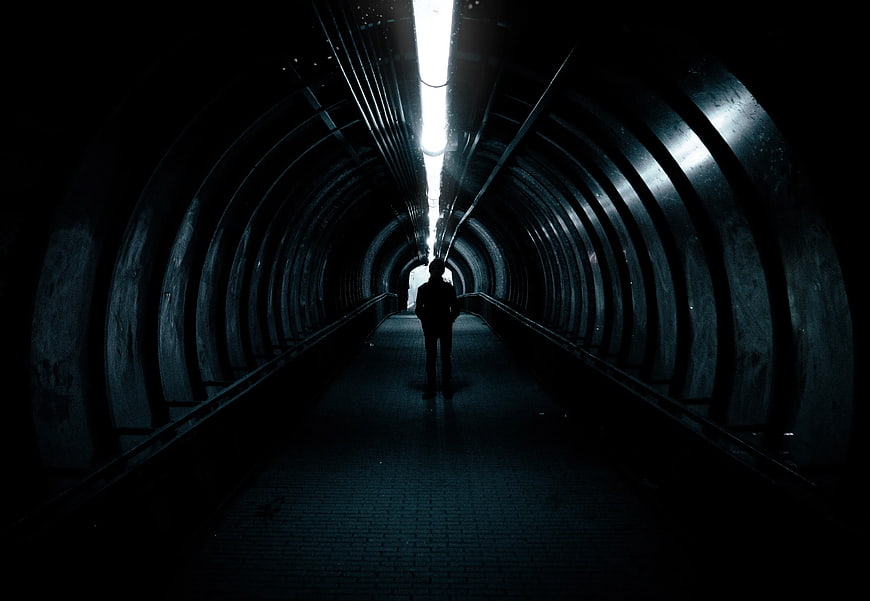 Silhouette of Man Standing in Dark Tunnel