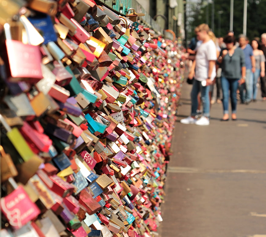 Colorful Love Locks on Bridge Railing with Blurred Tourists